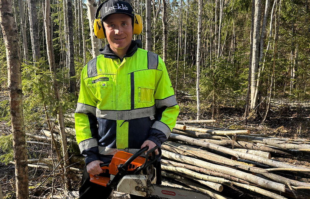 Henkilö moottorisahan kanssa metsässä.